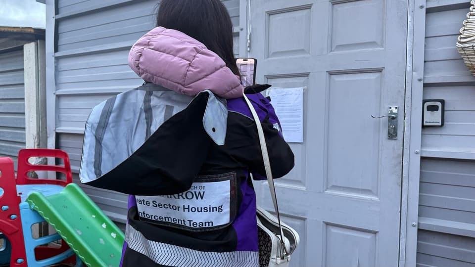 A housing officer from Hounslow Council taking a picture of the 'garden shed' being used to house a mother and child